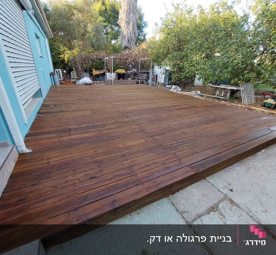 דק עץ רחב ליד בית עם קיר תכלת